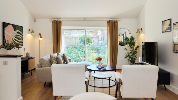 A modern living room with a sofa, two armchairs, a coffee table, and a TV. - The Abbey Mews House (London)
