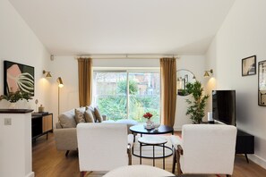 Ein modernes Wohnzimmer mit einer Couch, zwei Sesseln, einem Couchtisch und einem Fernseher.