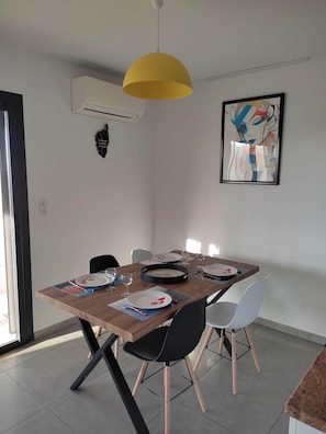 A dining area with a wooden table, black chairs, a yellow pendant light, and a framed abstract painting on the wall. - T3 sea view, terrace XL- Beaches 5min (propriano)