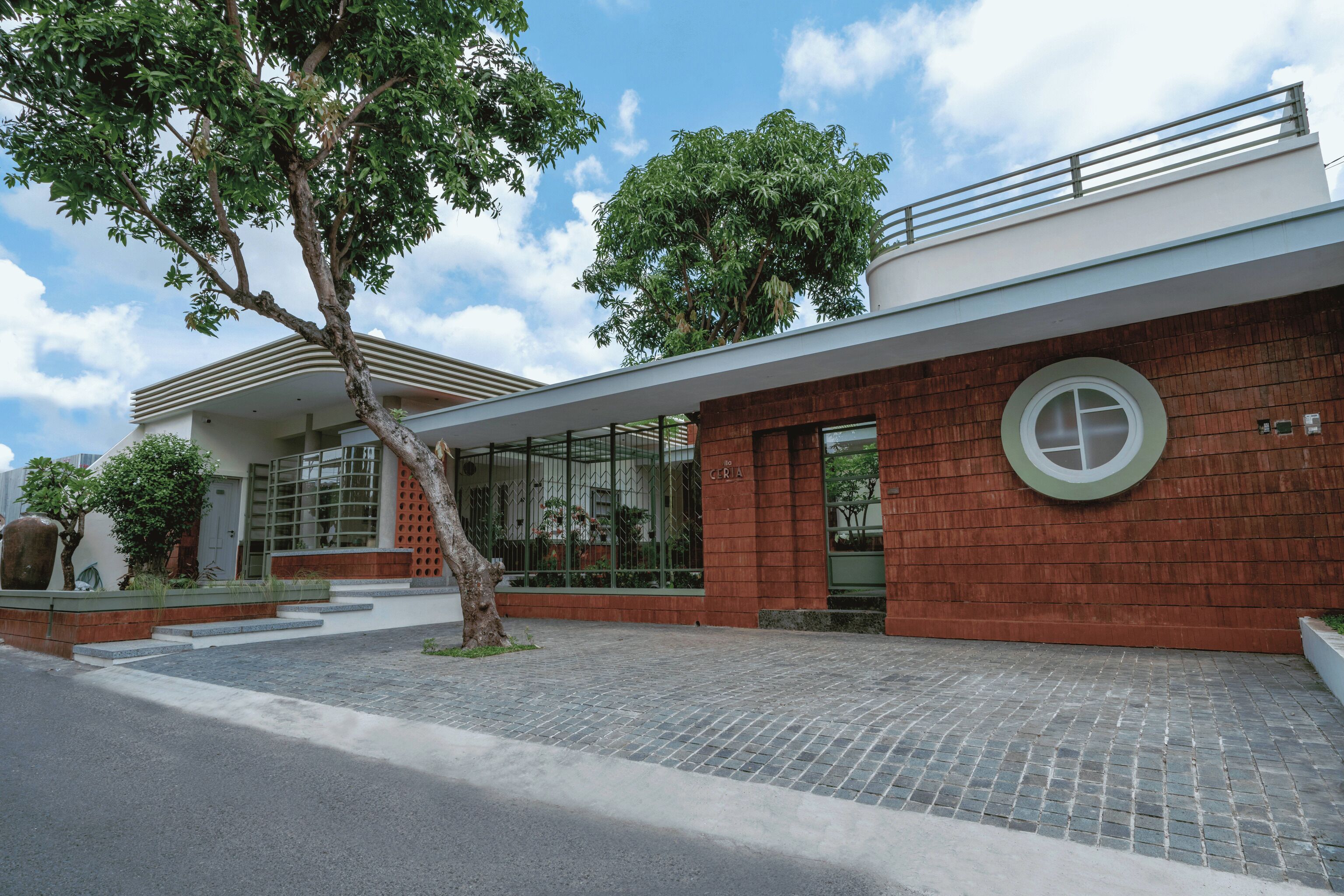 A modern building with a brick facade, large windows, and a circular window on the right.