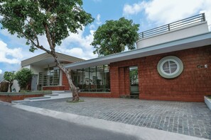 Un edificio moderno con fachada de ladrillo, ventanas grandes y una ventana circular a la derecha.
