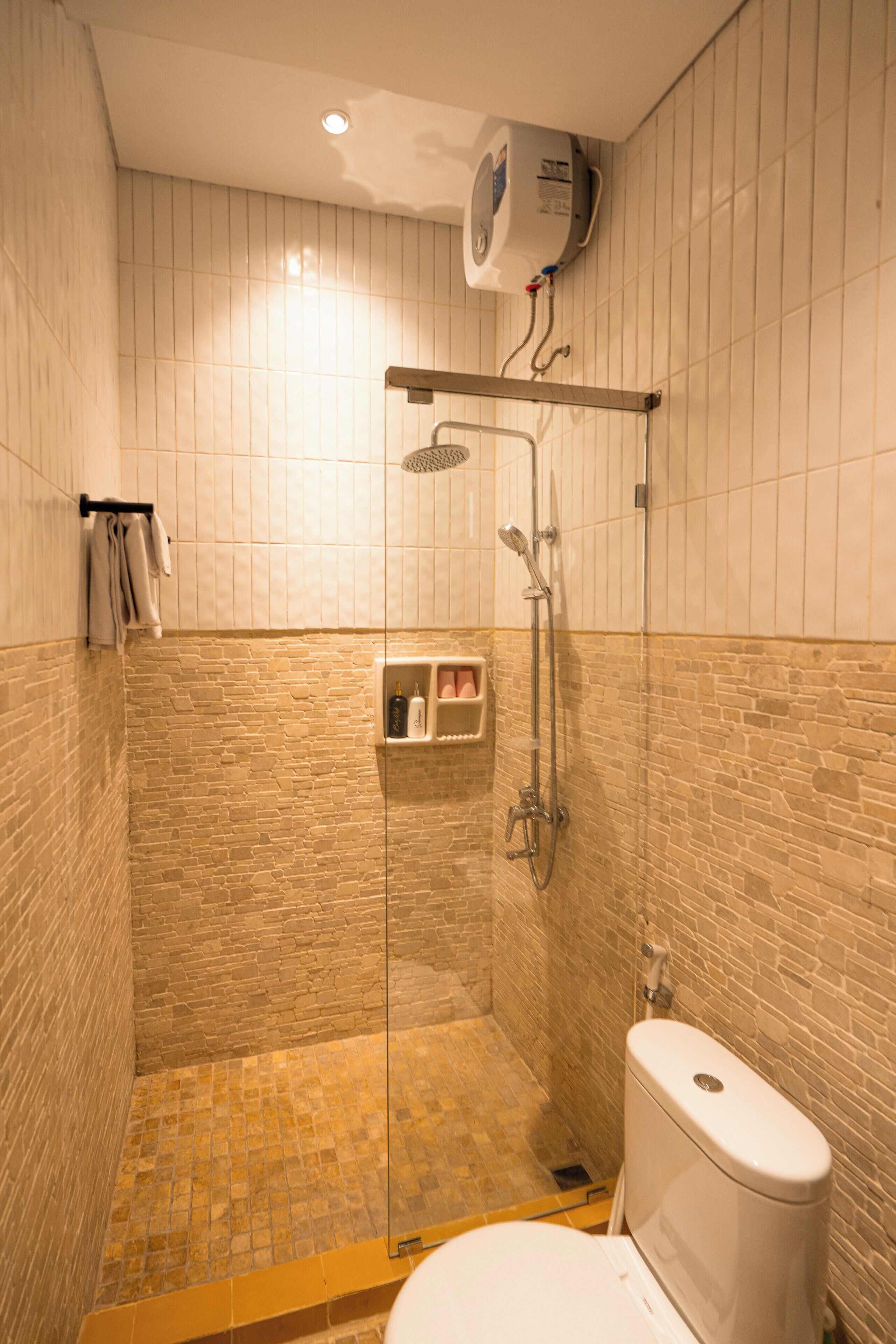 A shower with a glass door, a toilet, and a towel rack.
