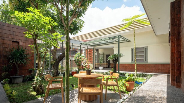 Un espace patio avec une table ronde et des chaises, entouré de plantes en pot et d’une clôture en bois.