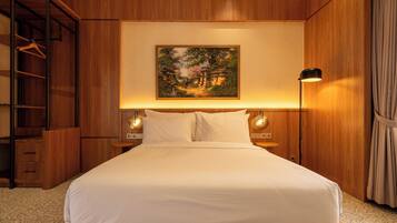 Una cama bien hecha con cabecera, un armario de madera y un cuadro en la pared.