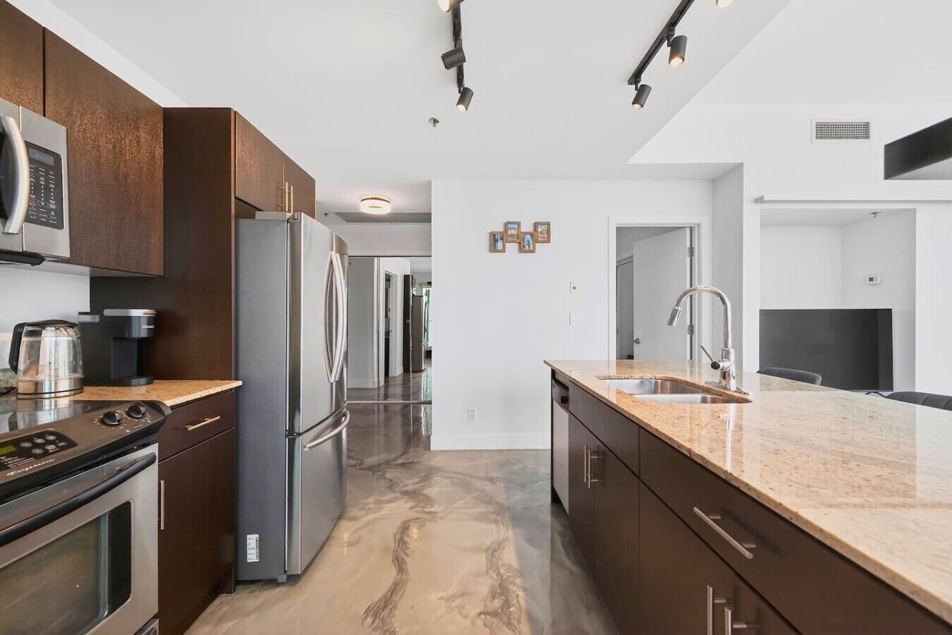 A modern kitchen with stainless steel appliances, a marble countertop, and a walk-in pantry.