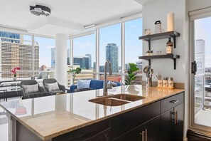 Eine moderne Küche mit einer großen Kochinsel, integriertem Spülbecken und Blick auf die Stadt.