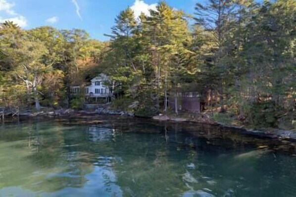 Una casa junto a un lago rodeada de árboles.