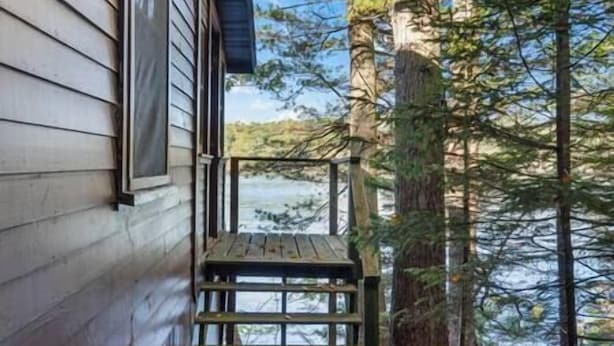 A wooden deck with a view of a lake and trees.