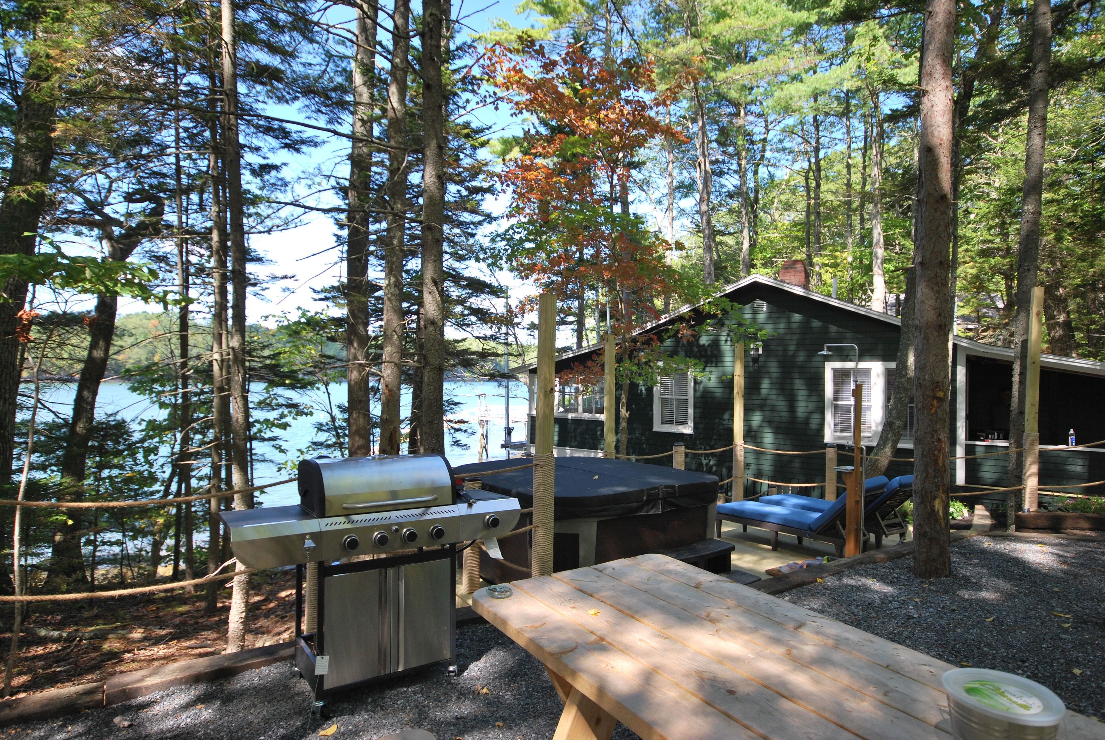 Cabana à beira do lago, com churrasqueira e mesa de piquenique.