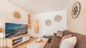 Una sala de estar con televisor, sofá y mesa de centro.