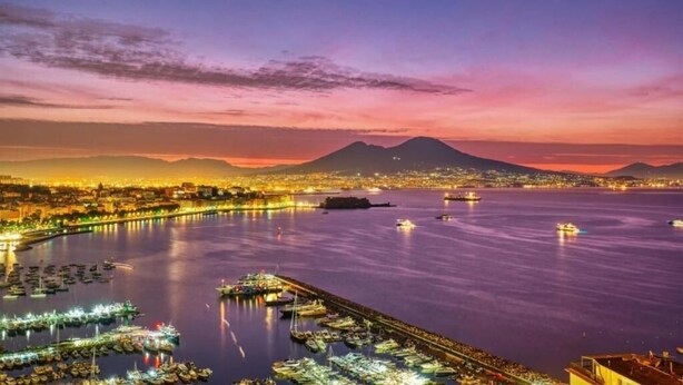 A marina with boats docked, a cityscape in the background, and a mountain range. - Prince Apartment (Napoli)
