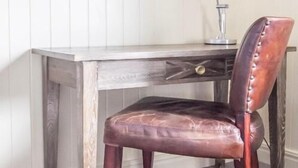 Ein Schreibtisch im Eckbereich mit einem Ledersessel, einer Lampe und zwei gerahmten Bildern an der Wand.