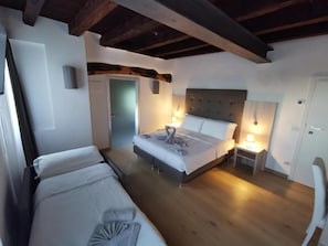 Une chambre à coucher avec un lit, des tables de chevet, une chaise et une porte.