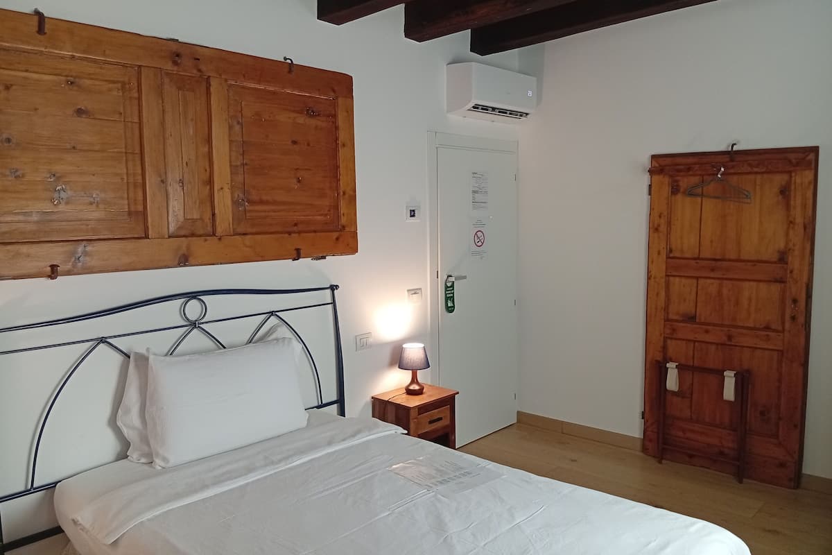 Un dormitorio con cama, armario de madera y una puerta con un cartel.