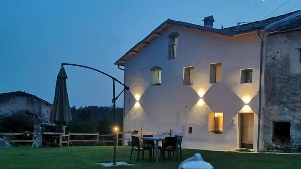 Un edificio bianco con molte finestre, una sala da pranzo con sedie e un tavolo con una lanterna.