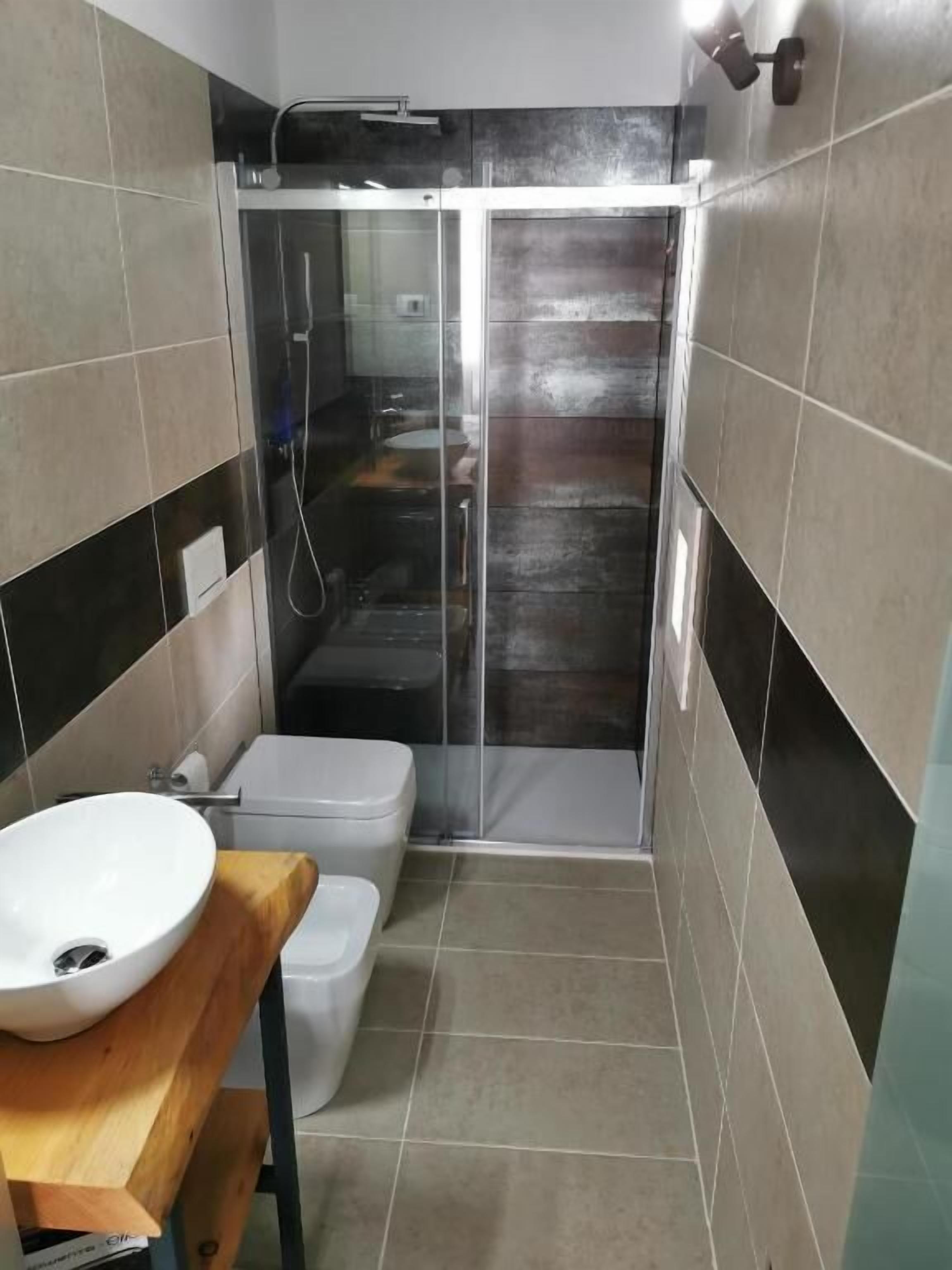 A bathroom with a shower enclosure, a toilet, and a sink.