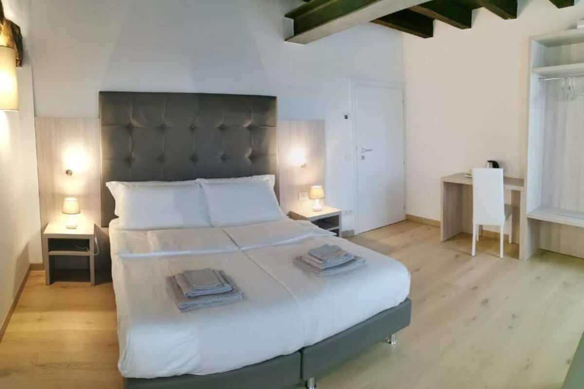 Un dormitorio con una cama grande, mesitas de noche con lámparas, un escritorio y un armario.