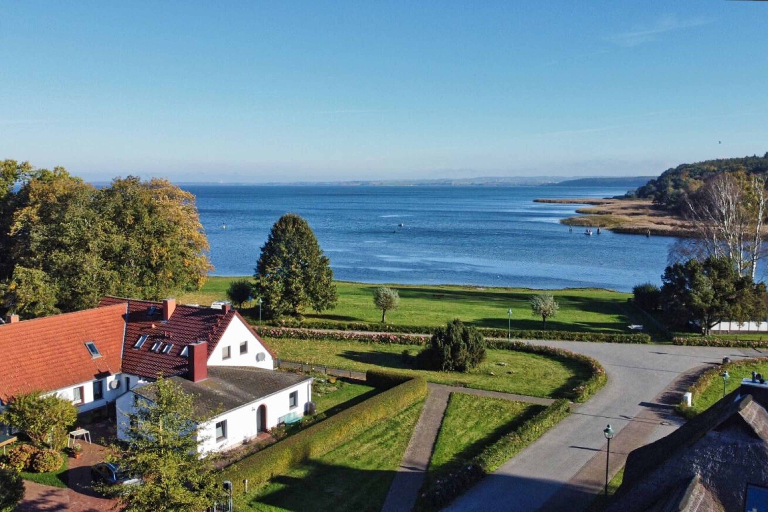 Et kystnært boligområde med huse, klar himmel og havudsigt.