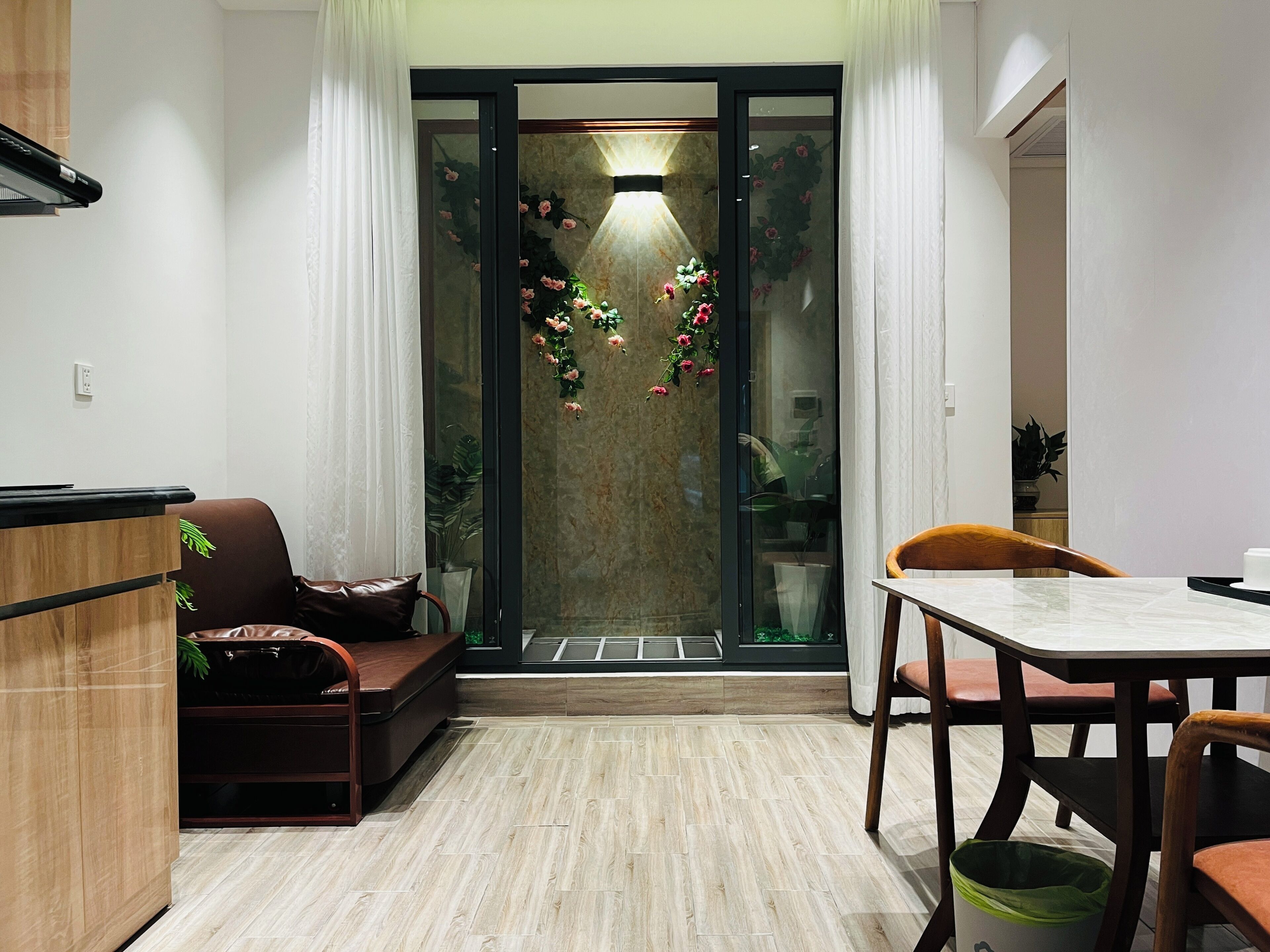 A modern living space with a sofa, a dining table, and a glass door leading to a balcony.