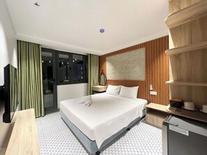 A hotel room with a bed, a desk, a mirror, a wardrobe, and a window with curtains. - Sun Hotel Phu Quoc (An Thoi)