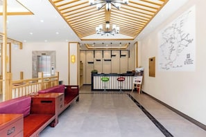 Un vestíbulo de hotel con una recepción, zona de estar y un mapa en la pared.