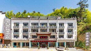 Een hotel met meerdere verdiepingen in traditionele bouwstijl, met balkons en een centrale ingang.
