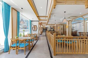 Ein modernes Restaurantambiente mit Holztischen, einem zentralen Gang und Blick auf die Straße.