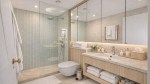 A modern bathroom with a glass shower enclosure, a toilet, a sink with a mirror above, and a vanity with towels and toiletries. - Serene 3-Bed Retreat for 6 - Elegant Central Home (London)
