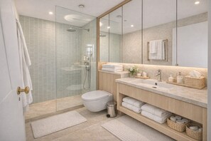 A modern bathroom with a glass shower enclosure, a toilet, a sink with a mirror above, and a vanity with towels and toiletries. - Serene 3-Bed Retreat for 6 - Elegant Central Home (London)