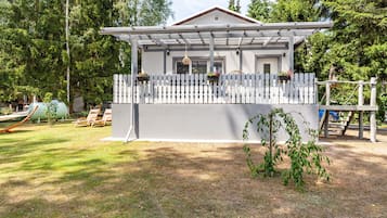 Ein Haus mit weißer Fassade, einer Veranda mit weißem Zierzaun und einem kleinen Garten.