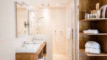 A modern bathroom with a large bathtub, two sinks, a wooden vanity, and a shower area.