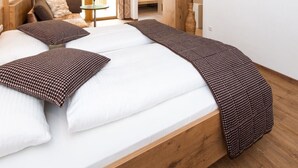 A bedroom with a large bed, wooden beams, a TV, and a view of the outdoors. - Weißes Rössl (Muehldorf)