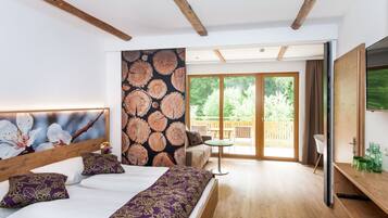 A bedroom with a bed, a wooden headboard, a large window, and a view of the outdoors.