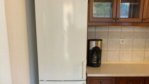 Eine Küche mit einem weißen Kühlschrank, Holzschränken und einer gefliesten Spritzschutzwand.