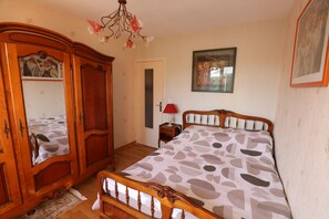 Un dormitorio con cama de madera, un armario, un espejo, una mesita de noche y una araña.