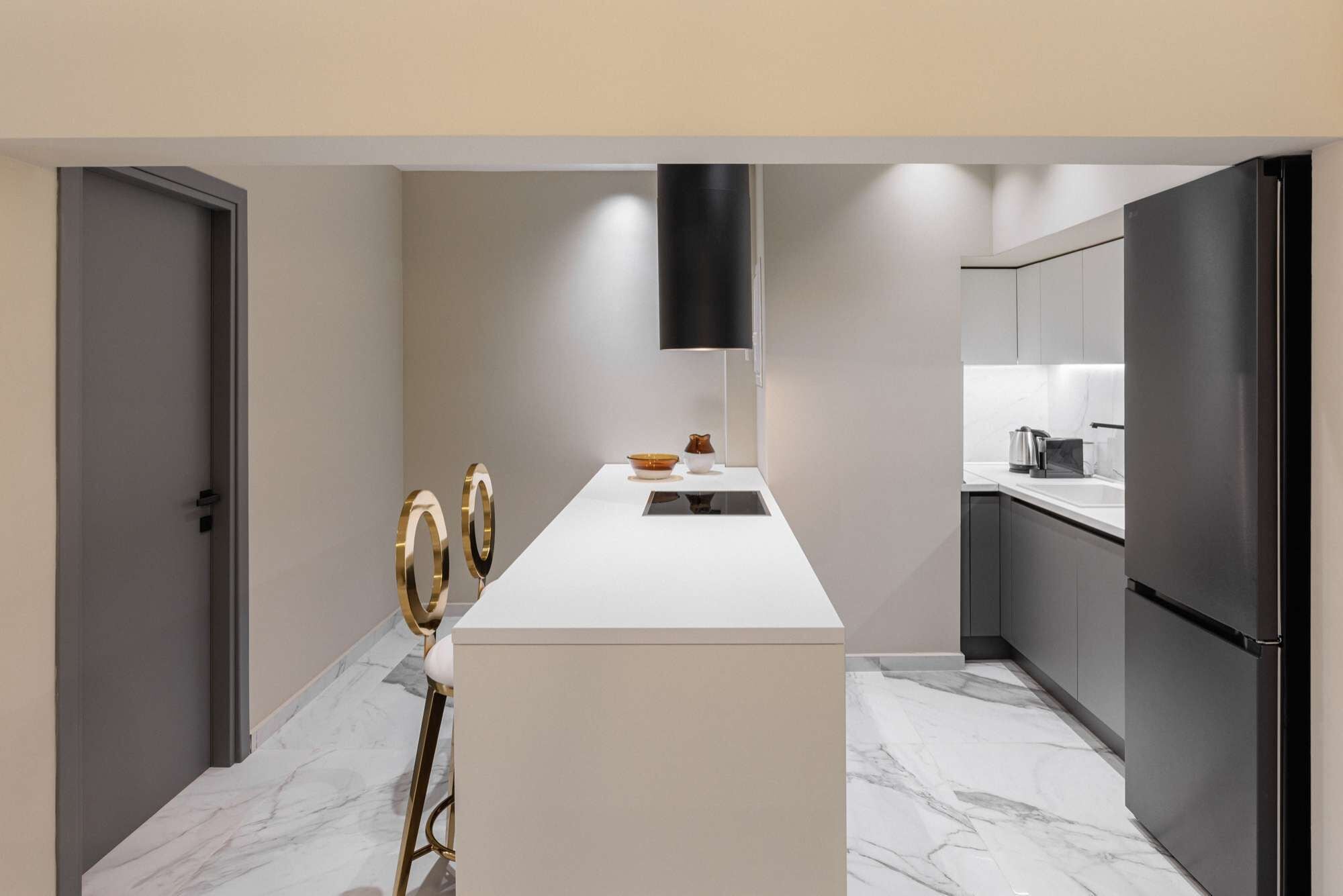 Een moderne keuken met een marmeren vloer, een wit aanrecht en een zwarte koelkast.