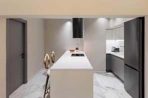 Eine moderne Küche mit Marmorboden, einer weißen Arbeitsplatte und einem schwarzen Kühlschrank.