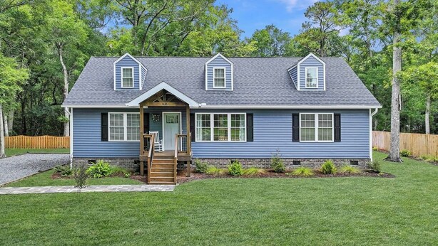 A two-story house with a front porch, a small front yard, and a wooden fence. - Dog Friendly! 254 a nite! 4Bed 3Bath! Free Island Parking! Just a skip to Beach! (Ocean Isle Beach)