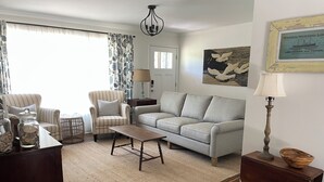 A living room with a sofa, armchair, coffee table, and a lamp. - Dog Friendly! 254 a nite! 4Bed 3Bath! Free Island Parking! Just a skip to Beach! (Ocean Isle Beach)