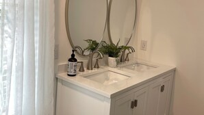 A bathroom with a double sink vanity, two round mirrors, a potted plant, and a bottle of hand soap. - Dog Friendly! 254 a nite! 4Bed 3Bath! Free Island Parking! Just a skip to Beach! (Ocean Isle Beach)