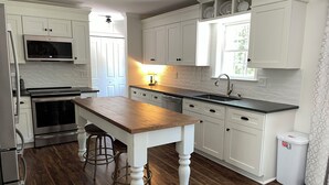 A kitchen with white cabinetry, a wooden island, stainless steel appliances, and a window with a view. - Dog Friendly! 254 a nite! 4Bed 3Bath! Free Island Parking! Just a skip to Beach! (Ocean Isle Beach)