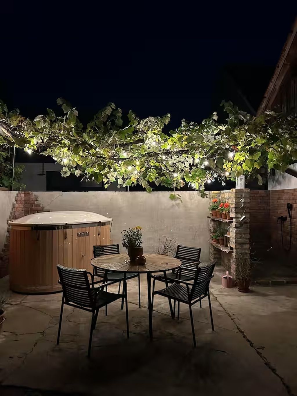 An outdoor patio with a hot tub, a round table, and chairs.