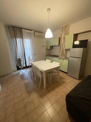 Una cocina compacta con una mesa de comedor, sillas, un refrigerador y un televisor.