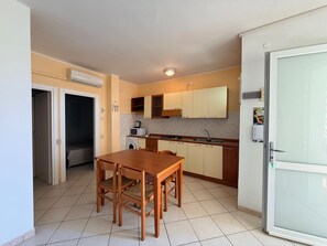 A compact kitchen with a dining table, a microwave, a washing machine, and a refrigerator.