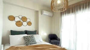 Ein Hotelzimmer mit einem Bett, einer Wand-Klimaanlage, einer runden Wanddekoration, einem Sessel und einem fenster mit Vorhängen.