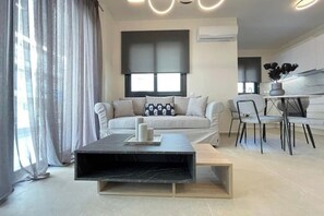 Una sala moderna con un sofá, una mesa de centro y un comedor con sillas.