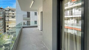 Ein modernes Gebäude mit Balkon, Glasgeländern und Blick auf umliegende Häuser.