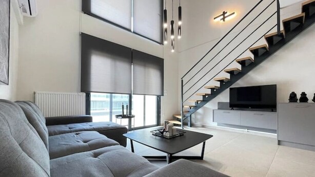 Ein modernes Wohnzimmer mit einer Couch, einem Couchtisch, einer Treppe und einem Fernseher.