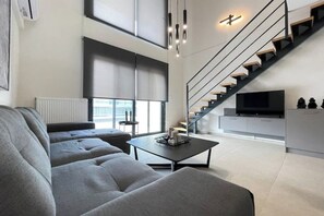 En moderne stue med sofa, sofabord, trappe og fjernsyn.