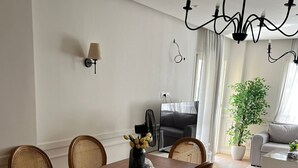 Un coin repas avec une table en bois et des chaises en osier, un lustre et une plante en pot.